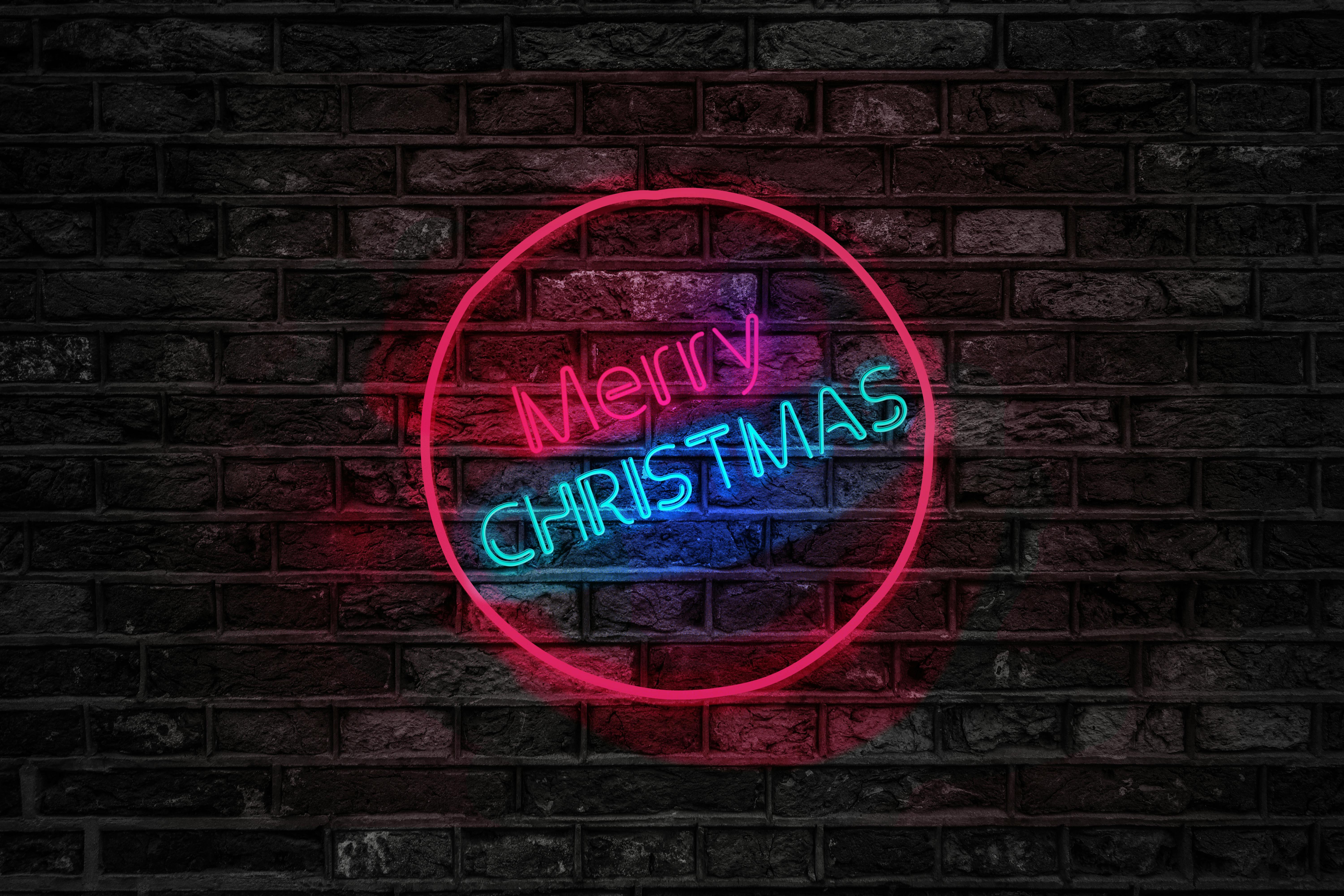 Merry Christmas v moderním stylu Neonový nápis „Merry Christmas“ svítí na cihlové zdi a vytváří moderní vánoční atmosféru spojenou s anglickými svátečními frázemi.